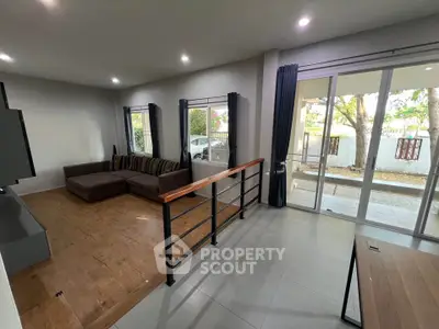 Spacious living room with modern decor and large windows opening to a garden view.