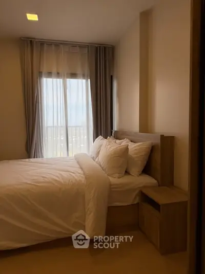 Cozy bedroom with modern decor and large window offering natural light.
