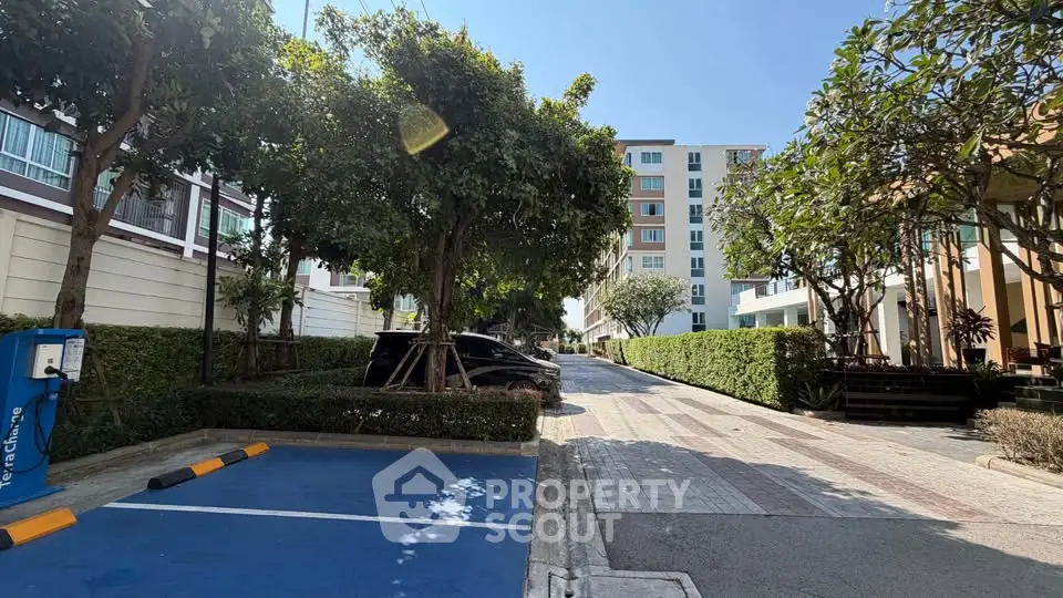 Charming residential building with lush greenery and spacious parking area.