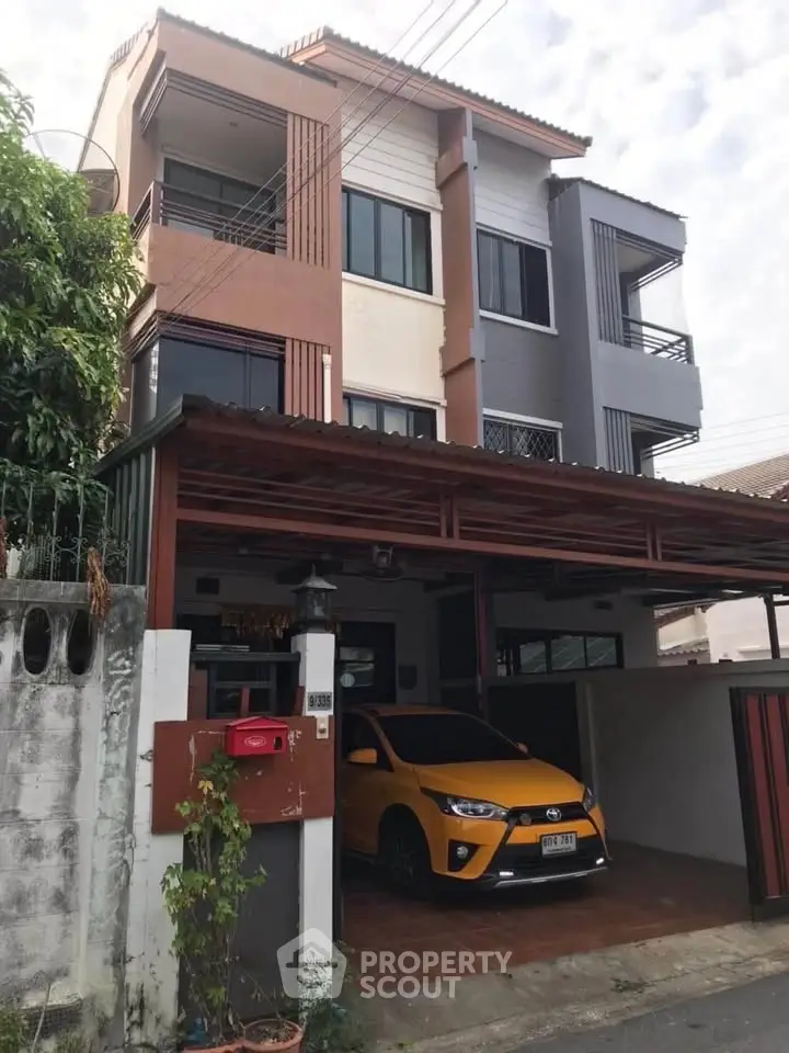 Modern three-story townhouse with carport and vibrant exterior design.