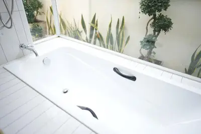 Luxurious bathroom with a sleek white bathtub and garden view.