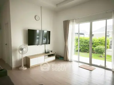 Spacious living room with modern decor and garden view through sliding glass doors.