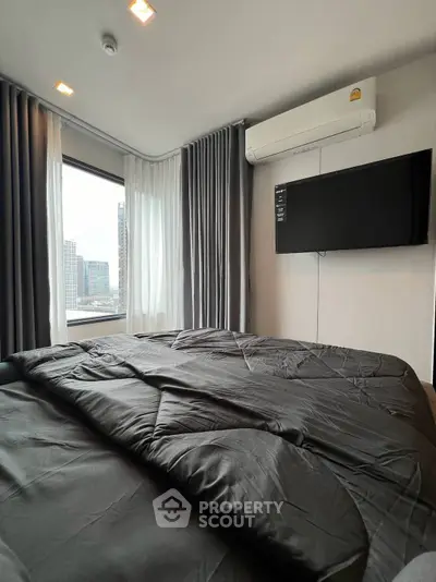 Modern bedroom with city view, featuring sleek black bedding and wall-mounted TV.