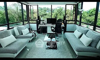 Stunning modern living room with panoramic windows and lush green views, perfect for relaxation and entertainment.