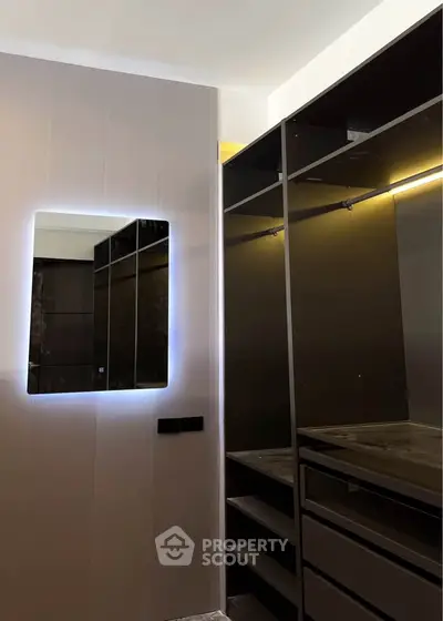 Modern walk-in closet with sleek shelving and illuminated mirror, perfect for luxury living.