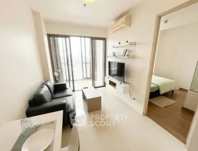 Modern living room with balcony access and sleek furnishings in a bright apartment.