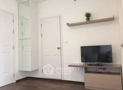 Modern living room with TV, wooden flooring, and minimalist decor