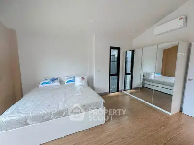 Modern bedroom with mirrored wardrobe and wooden flooring