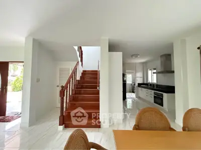 Spacious open-plan living area with elegant wooden staircase and modern kitchen.
