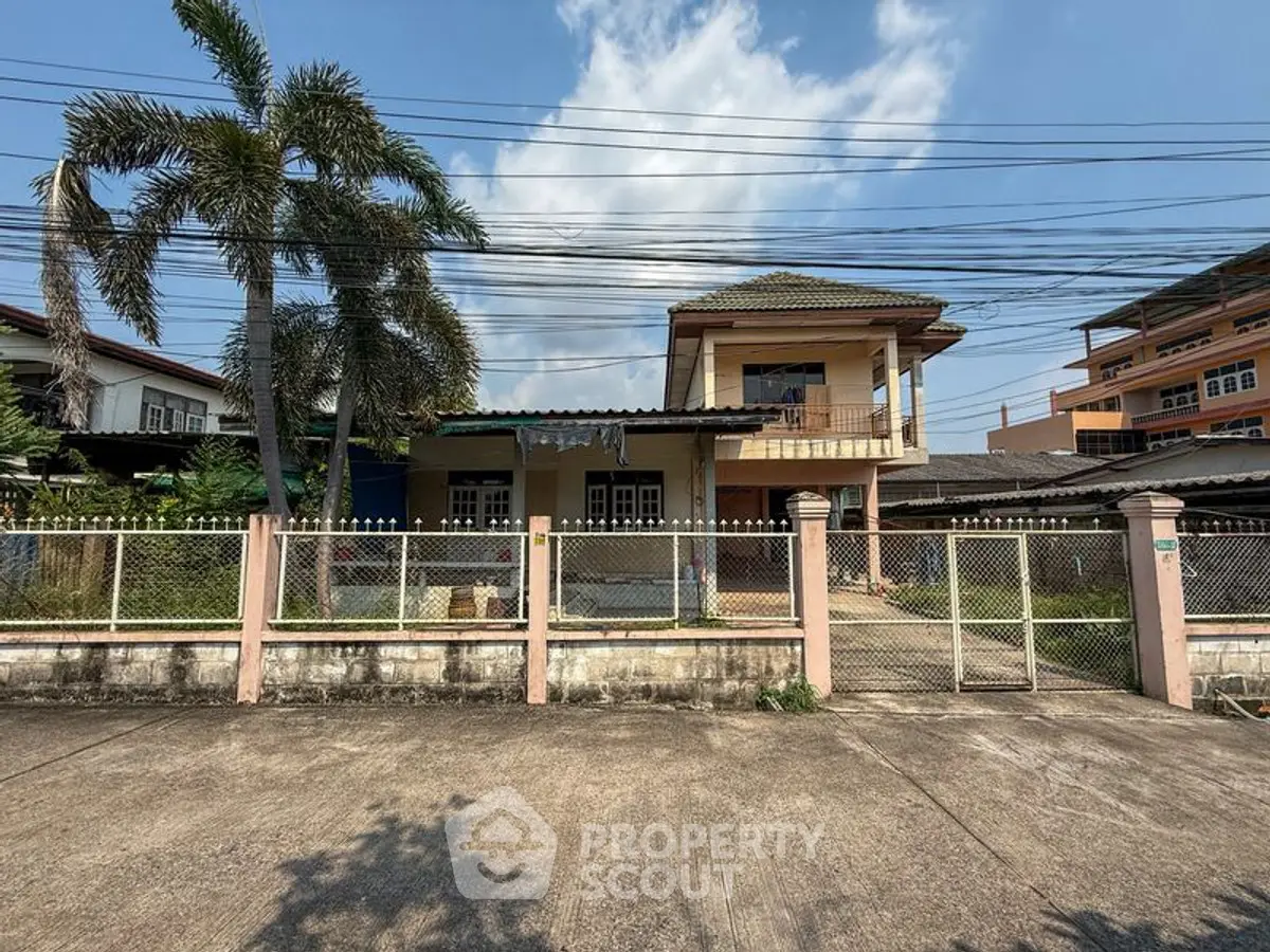 Charming two-story house with a spacious front yard and gated entrance, perfect for family living.