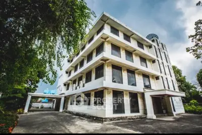 Stunning four-story building with modern architecture and lush greenery, perfect for commercial or residential use.