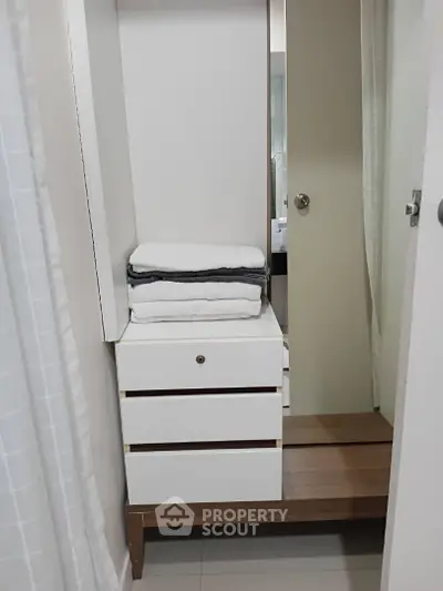 Compact bathroom storage with towels and mirror in modern apartment