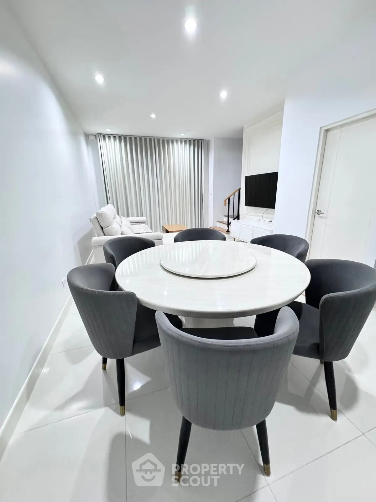 Modern dining area with elegant round table and plush chairs in a stylish living room.