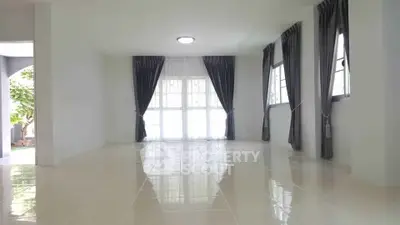 Spacious living room with large windows and elegant curtains, offering abundant natural light.