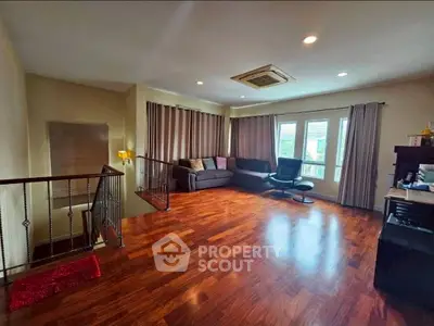 Spacious living room with hardwood floors and large windows in a modern home.