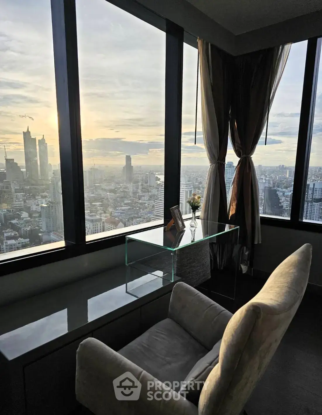 Luxurious high-rise apartment with stunning city skyline view at sunset, featuring elegant furnishings.