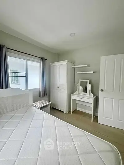Bright and airy bedroom with modern white furniture and large window.