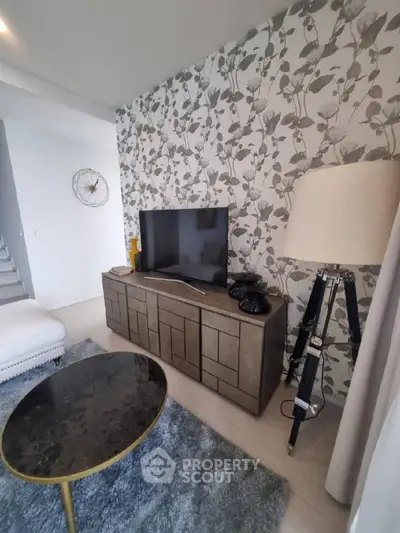 Stylish living room with modern decor, featuring a TV on a chic cabinet, elegant wallpaper, and a designer floor lamp.