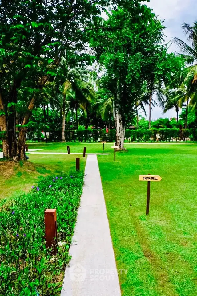 Lush green garden with pathway and tropical trees, perfect for relaxation.