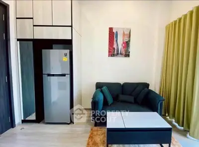 Modern living room with cozy sofa, stylish decor, and sleek refrigerator.