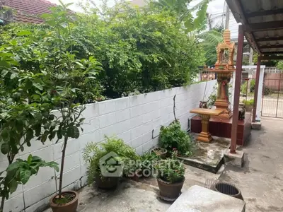 Charming garden area with lush greenery and traditional spirit house in a serene residential setting.