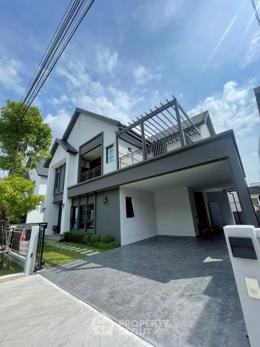 Modern two-story house with spacious driveway and lush greenery