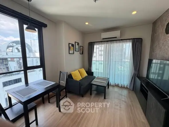 Modern living room with large windows, cozy seating, and stylish decor in a high-rise apartment.