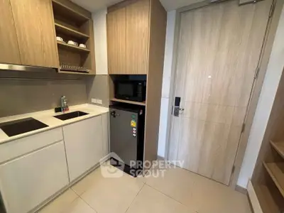Modern compact kitchen with sleek cabinetry and built-in appliances in a stylish apartment.