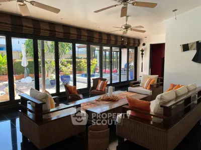 Spacious living room with large windows and stylish wicker furniture overlooking a lush garden.