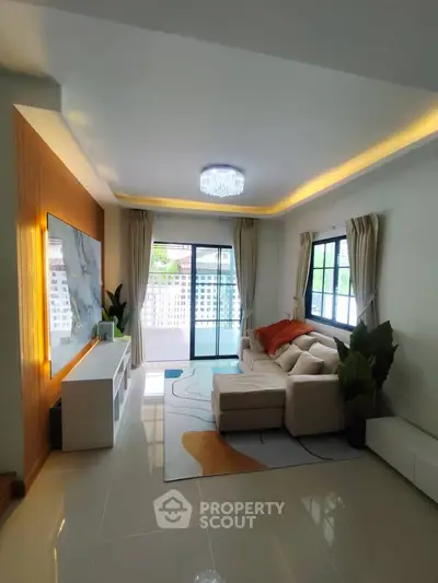 Spacious living room with modern decor and large windows leading to a balcony, perfect for relaxation.