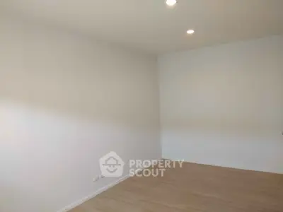 Spacious empty room with wooden flooring and recessed lighting, perfect for customization.