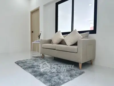 Modern living room with cozy beige sofa and plush rug in bright interior.