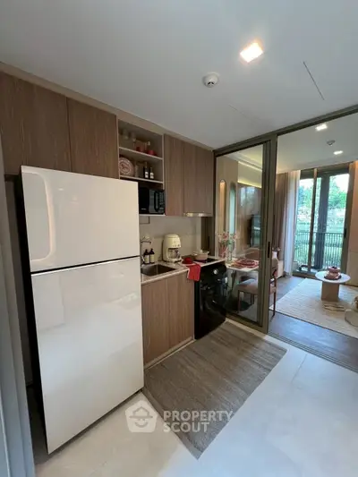Modern kitchen with sleek appliances and open layout leading to a bright dining area with balcony view.