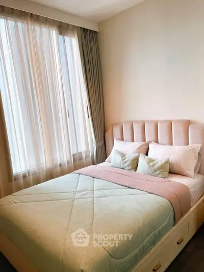 Cozy bedroom with elegant decor and natural light through sheer curtains.