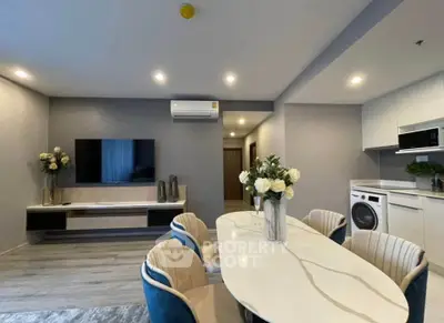Modern living room with elegant dining area and built-in appliances, featuring stylish decor and ambient lighting.