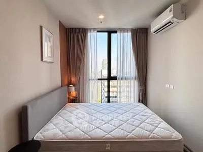 Modern bedroom with large window and city view, featuring a comfortable bed and stylish decor.