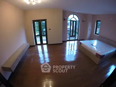 Spacious bedroom with large windows and wooden flooring