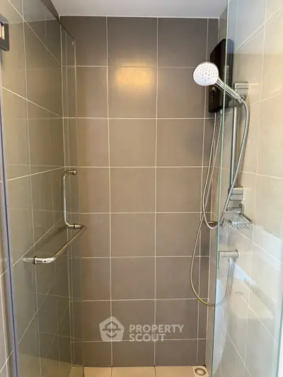 Modern tiled shower with glass door and sleek fixtures in a contemporary bathroom.