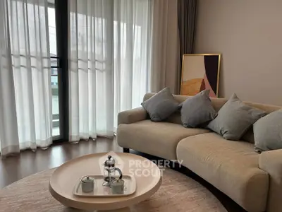 Elegant living room with modern sofa, stylish decor, and large windows for natural light.