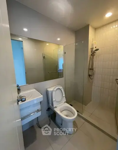 Modern bathroom with glass shower and sleek fixtures in contemporary apartment.