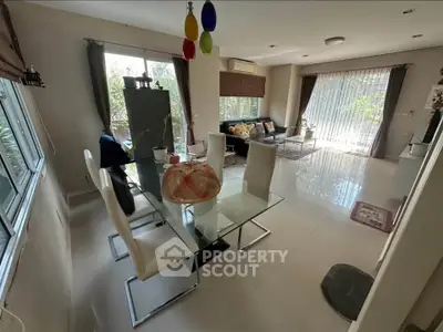 Spacious living room with modern glass dining table and large windows for natural light.