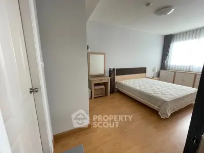 Spacious bedroom with wooden flooring and modern furniture