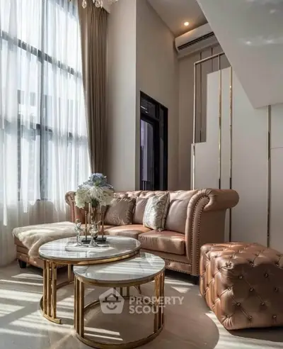 Luxurious living room with high ceilings, elegant furniture, and large windows for natural light.