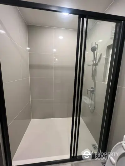 Sleek modern bathroom with a spacious walk-in shower featuring elegant tiling, glass enclosure, and high-quality fixtures, perfect for a refreshing start to the day.