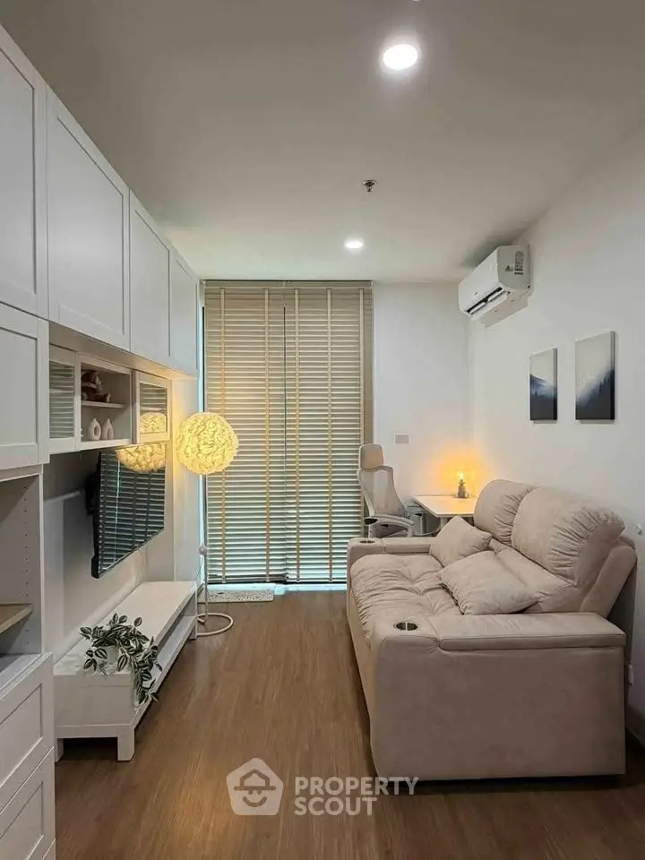 Cozy living room with modern decor, featuring a plush sofa, stylish lighting, and sleek wooden flooring.