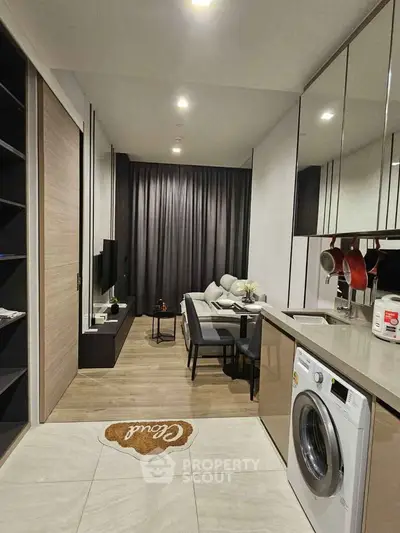 Modern open-plan living room with kitchen featuring sleek design and washing machine.