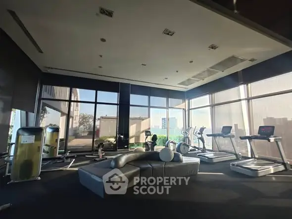 Spacious modern gym with state-of-the-art equipment and large windows offering natural light.