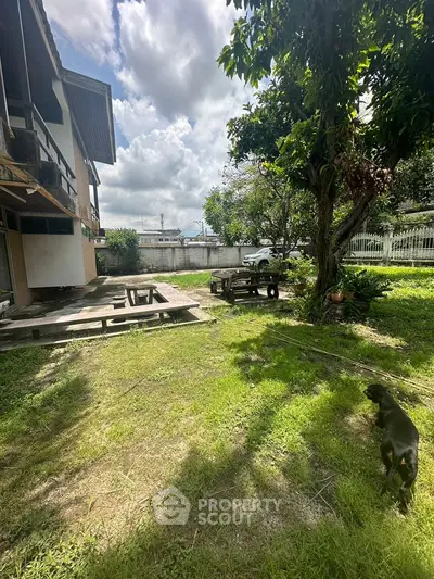 Spacious backyard with lush greenery and a charming wooden deck, perfect for outdoor relaxation.