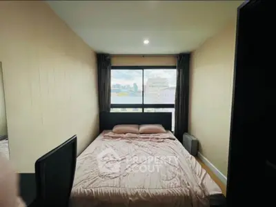 Cozy bedroom with large window offering city view, perfect for urban living.