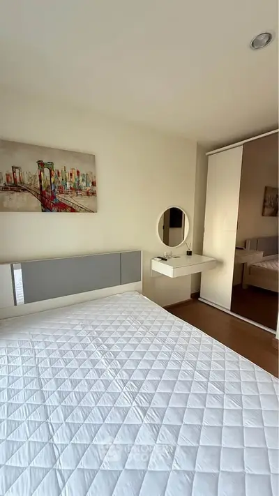 Modern bedroom with sleek design, featuring a stylish bed, mirrored wardrobe, and elegant vanity area.